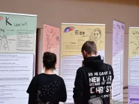 Zwei Teilnehmende betrachten die Ausstellung "Etc. Fachkräfte fragen - Queere Jugendliche antworten" vom Kompetenzzentrum geschlechtergerechte Kinder- und Jugendhilfe Sachsen Anhalt e.V.